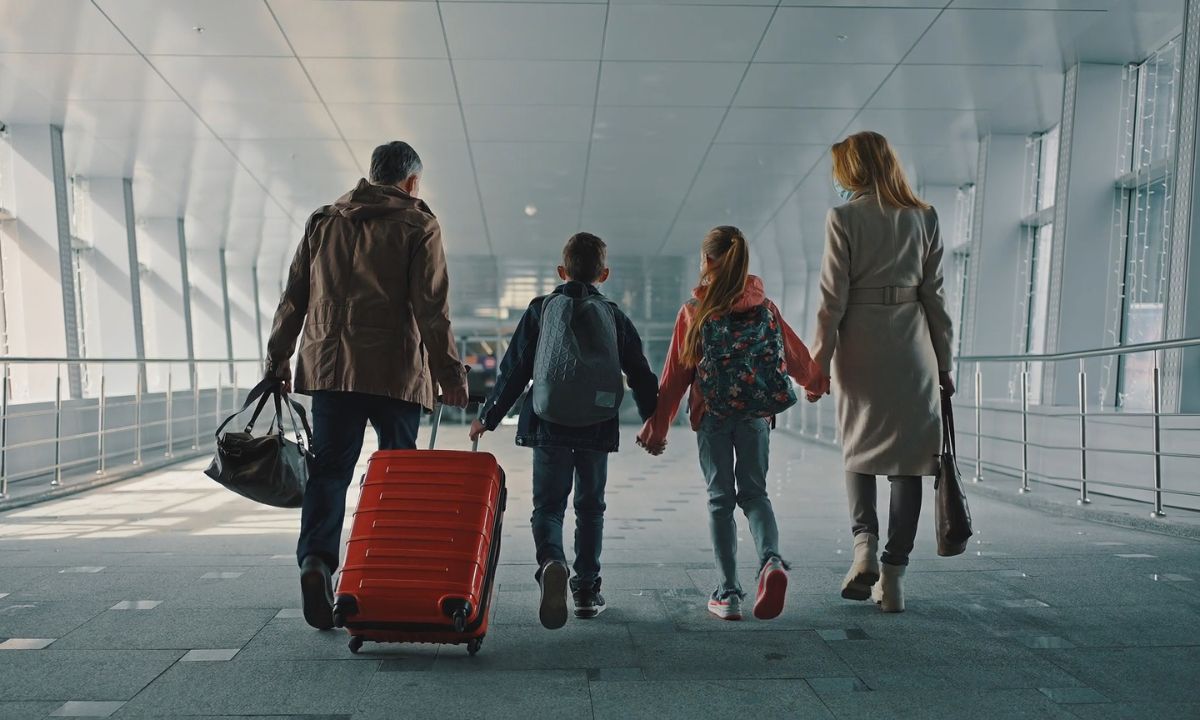 dvoje dece i majka i otac kreću na porodično putovanje sa koferom i torbom u ruci